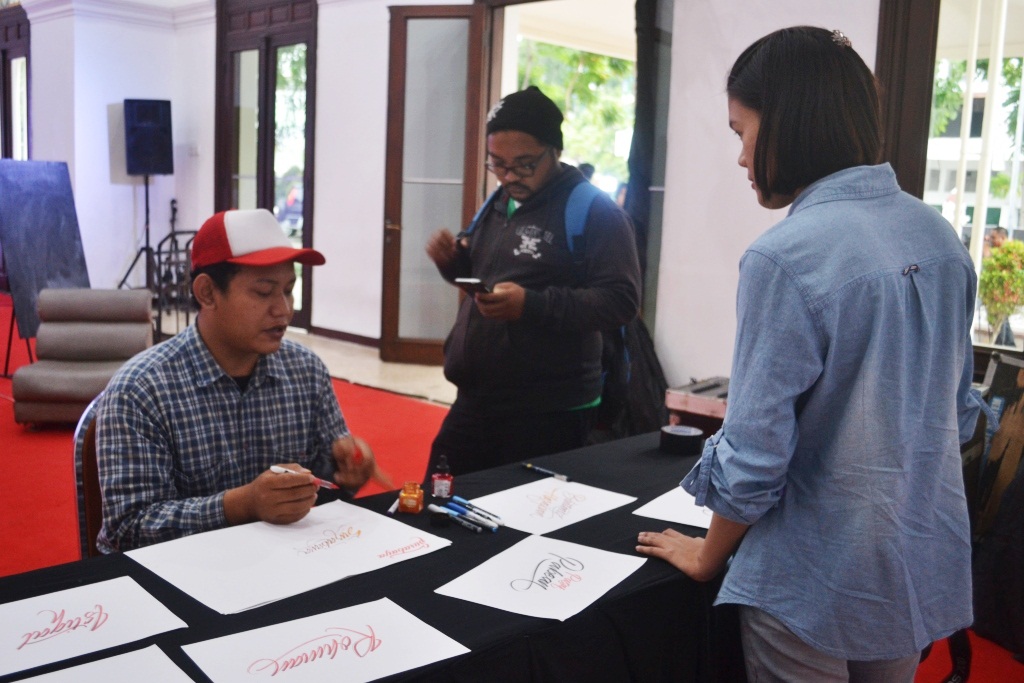 Alviant Helmi(desainer grafis) sedang melakukan live demo pembuatan kaligrafi dengan teknik brush